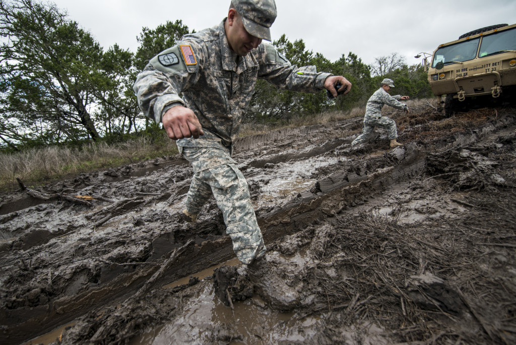 Sgt. Robert Gonzales, maintenance squad leader for the 277th Engineer Company (Horizontal), of San Antonio, Texas, jumps over a mud trail after helping recover a vehicle that had been stuck from another unit at Camp Bullis, Texas, March 22. (U.S. Army photo by Sgt. 1st Class Michel Sauret)